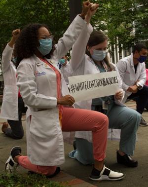 Medical students kneel with fists in air